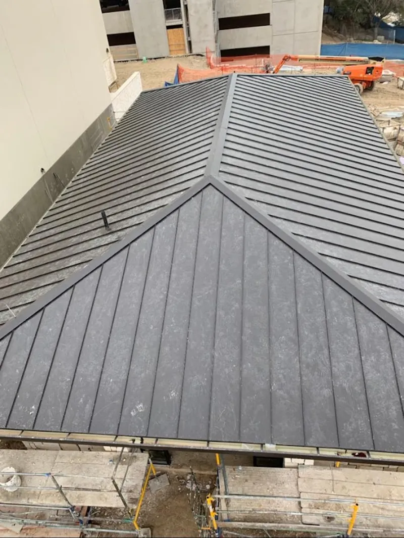 Commercial metal roof construction with crane equipment in Mililani Town